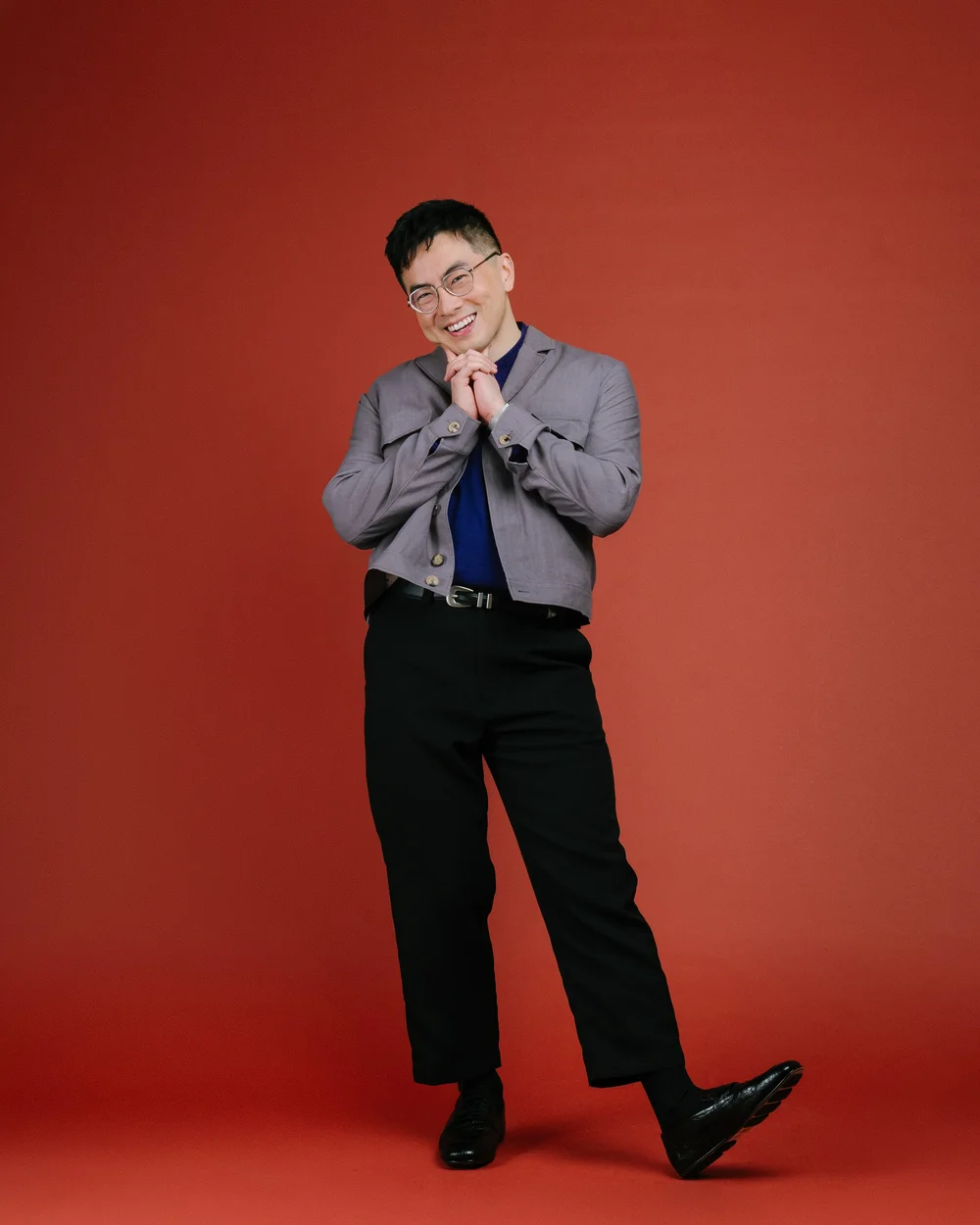 Bowen Yang posing playfully against a red backdrop for NYC Pride 2026