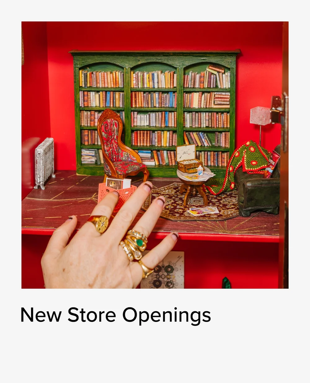 Hand in gold rings in front of a red library display at a store opening