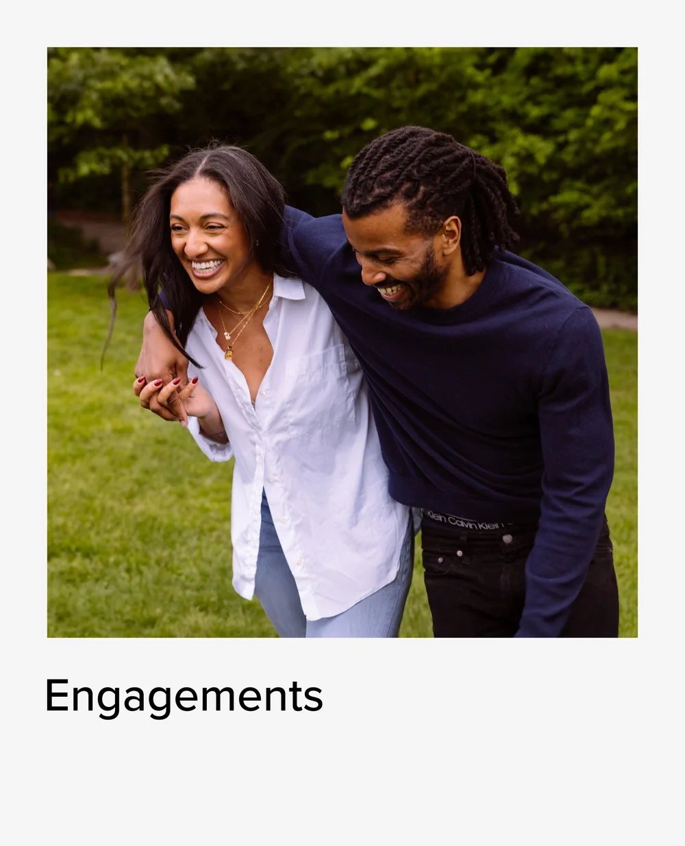 Engaged couple laughing arm in arm in a park, engagement photos
