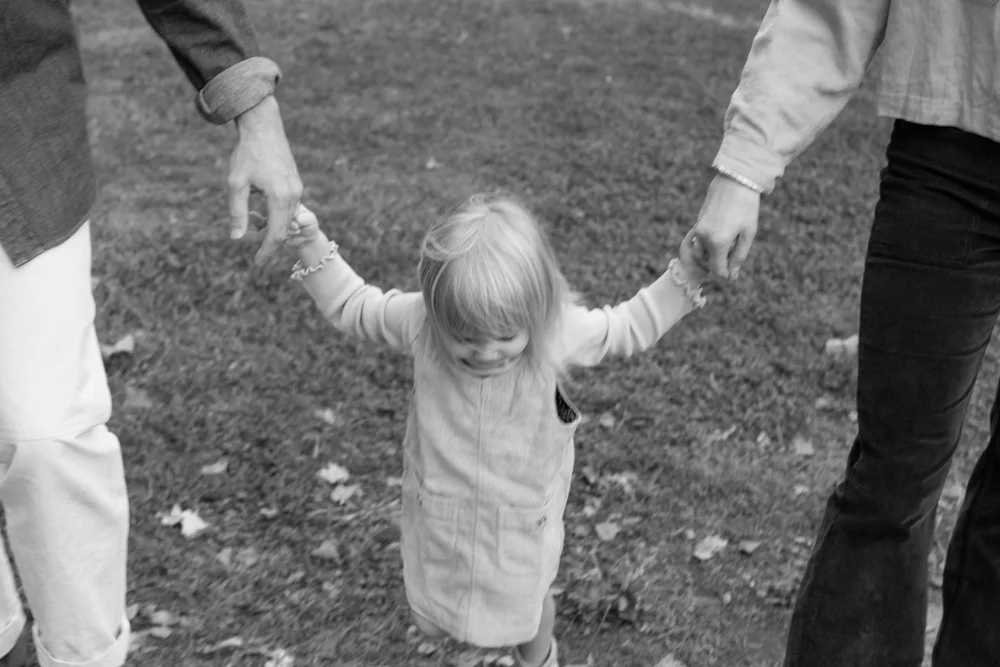 toddler-holding-parents-hands-black-and-white.jpg