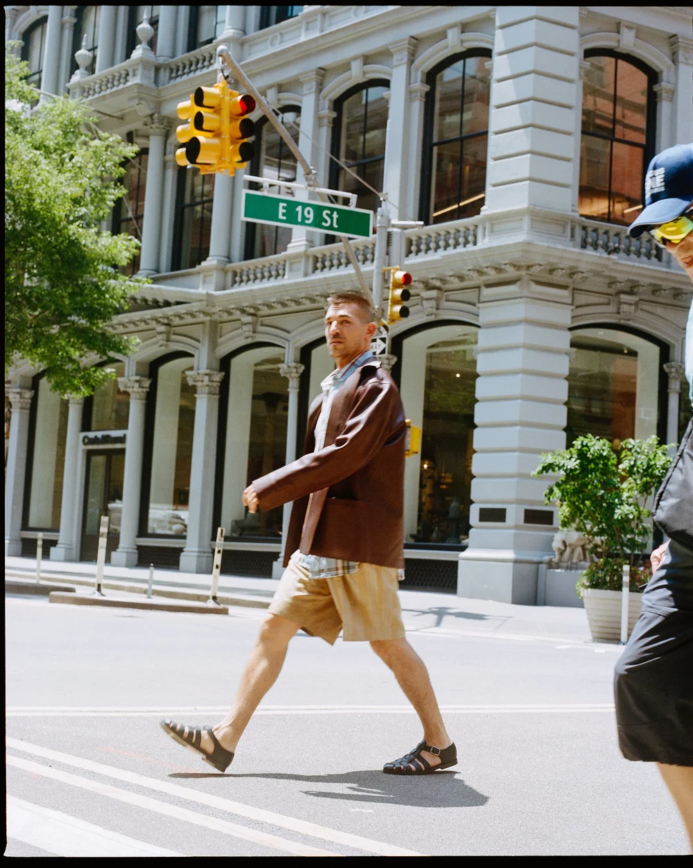Matt Rogers walking past a Broadway street sign in NYC for ODDA magazine