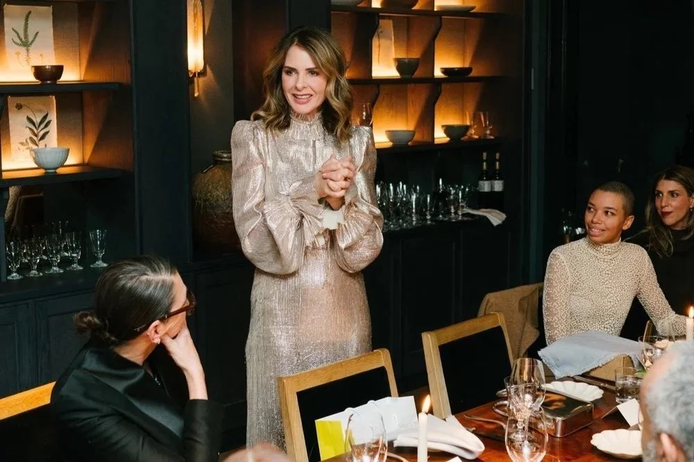 Guest in a sequin top raising a glass at the Trinny London VIP dinner