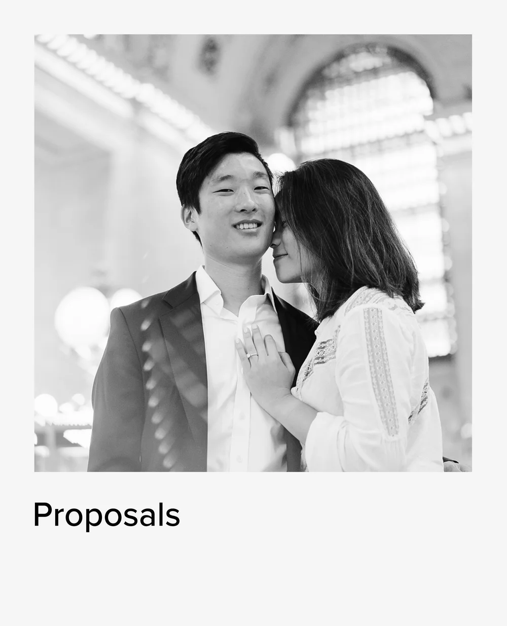 Black and white photo of a couple embracing after a proposal at Grand Central